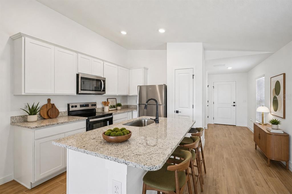 A kitchen features white cabinets, granite countertops, stainless steel appliances, and a central island — 15306 SCAUP DUCK ROAD, WEEKI WACHEE, FL