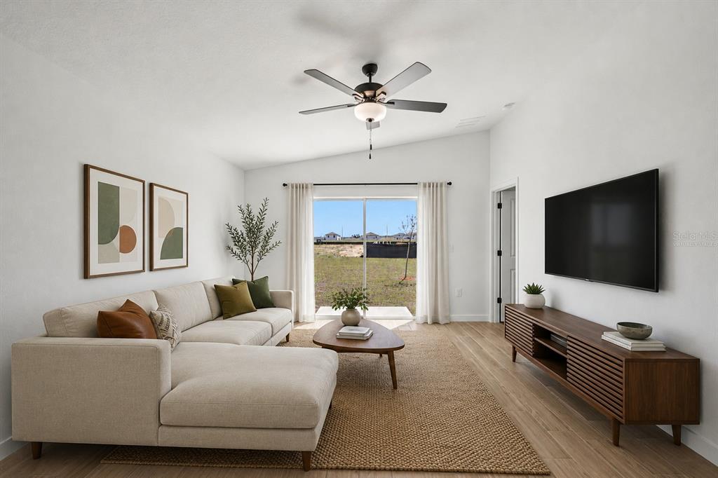 A living room features a sectional sofa, a wooden media console, and a sliding glass door — 15306 SCAUP DUCK ROAD, WEEKI WACHEE, FL