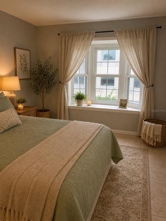 A bedroom features a green bedspread, a bay window with curtains, and a potted plant — 2651 MICHAEL PLACE UNIT 307, DUNEDIN, FL