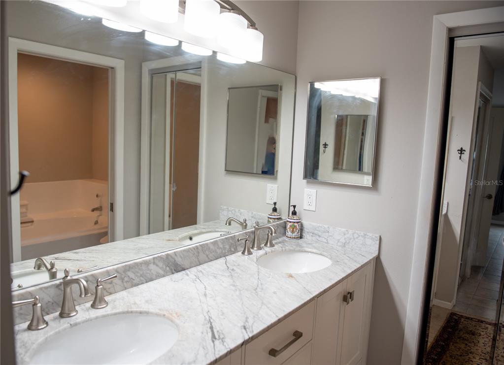 A bathroom features a double vanity with a marble countertop, dual sinks, and a large mirror — 2651 MICHAEL PLACE UNIT 307, DUNEDIN, FL