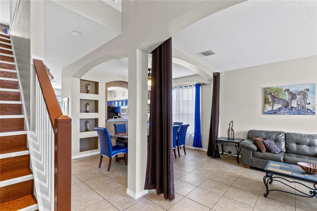 A dining room with blue chairs, tile flooring, and a staircase leading to the upper level — 180 HIDEAWAY BEACH LANE, KISSIMMEE, FL