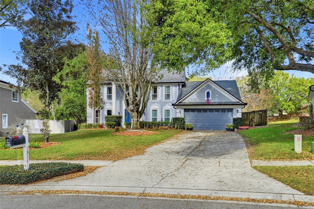 A two-story light blue house with a front-facing garage and a concrete driveway — 1311 OLYMPIA PARK CIRCLE, OCOEE, FL