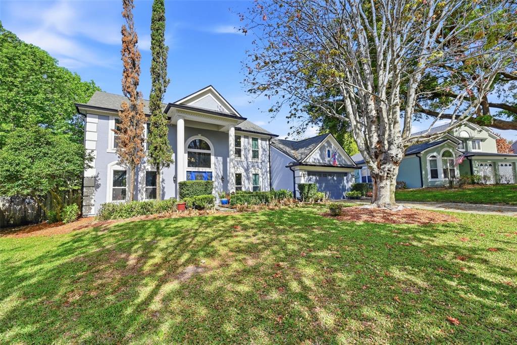 A two-story gray house with white trim and a front-facing garage sits on a lawn — 1311 OLYMPIA PARK CIRCLE, OCOEE, FL