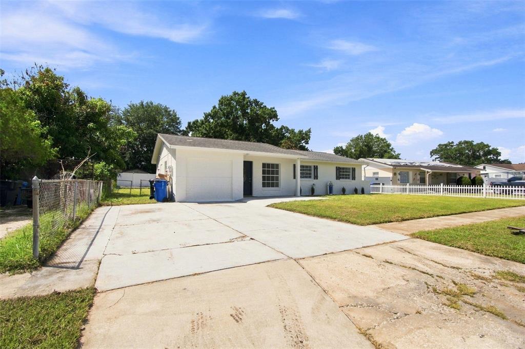 A single-story white house with a concrete driveway and a white picket fence — 1719 JULIAN LN DRIVE, TAMPA, FL