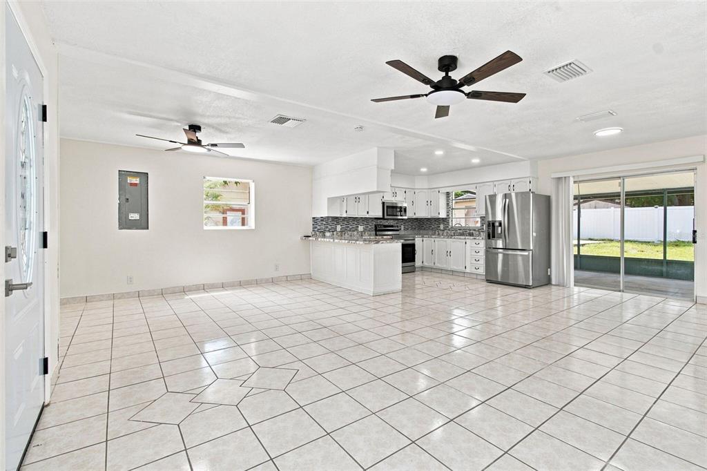 An open-concept kitchen and living area with white cabinets, stainless appliances, and tiled floors — 1719 JULIAN LN DRIVE, TAMPA, FL