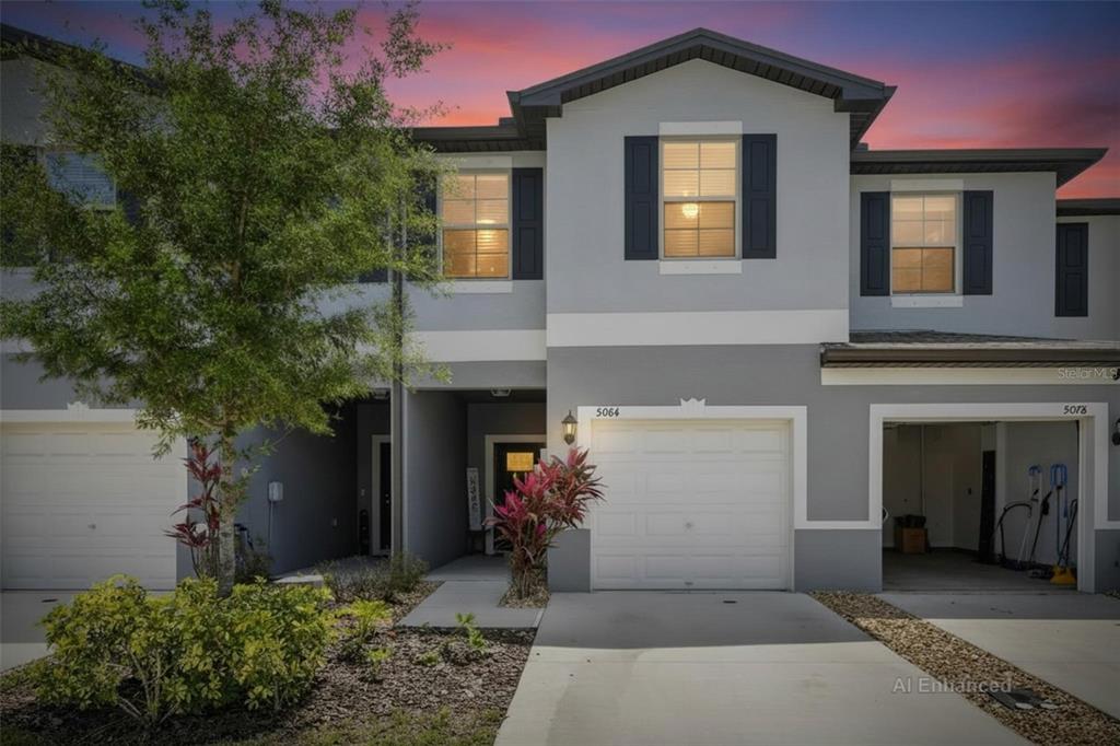 A two-story townhouse exterior features a gray facade, white trim, and a concrete driveway — 5084 FORUM BLVD, HOLIDAY, FL