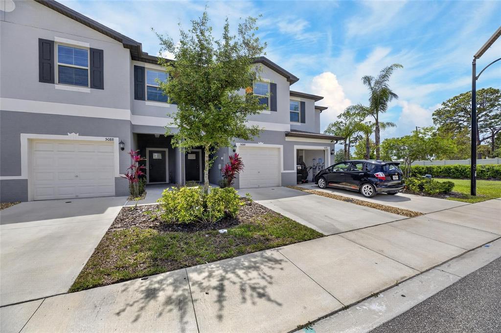 A two-story townhouse exterior features gray siding, white trim, and attached garages with concrete driveways — 5084 FORUM BLVD, HOLIDAY, FL