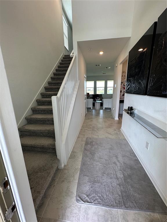 An entryway features a carpeted staircase, tile flooring, a floating shelf, and a hallway view — 8946 FLUFFY LIE COURT, DAVENPORT, FL