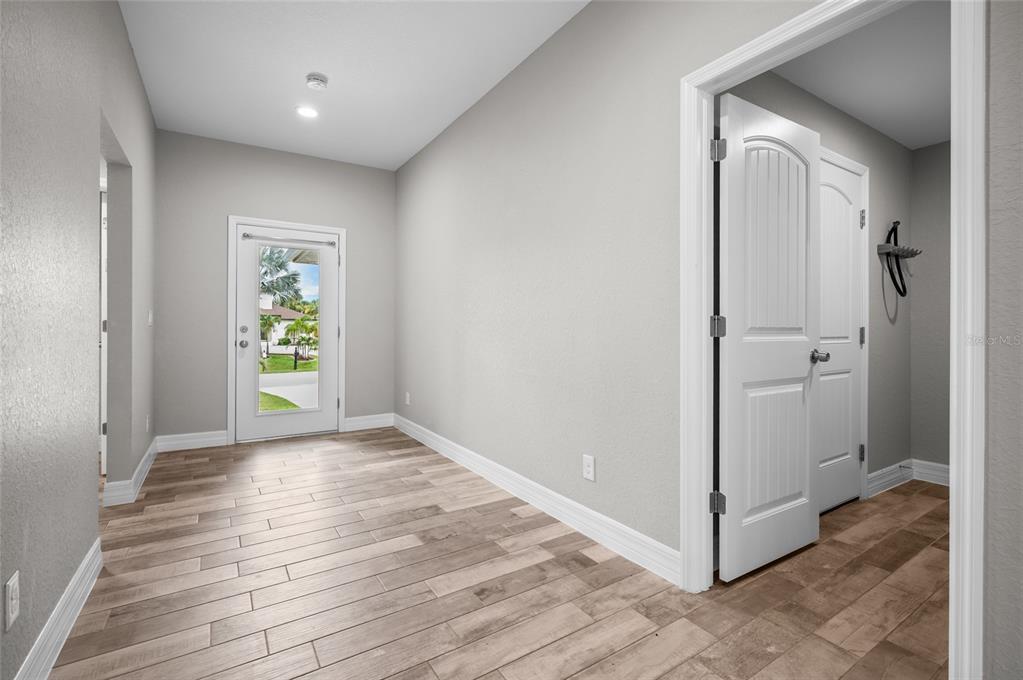 A hallway with light wood-look tile flooring, gray walls, and a glass-paneled exterior door — 315 SWEETWATER DRIVE, ROTONDA WEST, FL