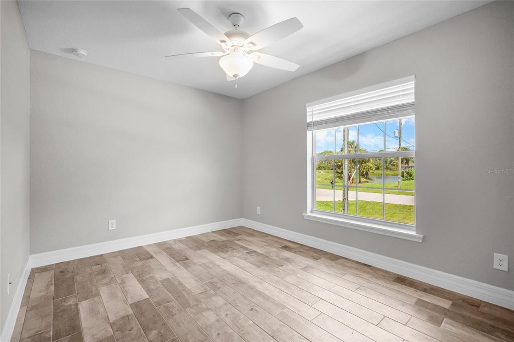 An empty bedroom features light gray walls, wood-look tile flooring, a ceiling fan, and a window — 315 SWEETWATER DRIVE, ROTONDA WEST, FL