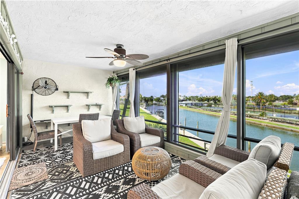 A sunroom with wicker furniture, a patterned rug, and large windows overlooking a canal — 6500 FLOTILLA DRIVE UNIT 235, HOLMES BEACH, FL