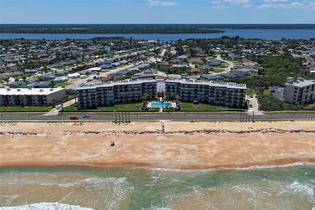 An aerial view shows a beachfront condominium complex with a pool and surrounding residential neighborhood — 2700 OCEAN SHORE BOULEVARD UNIT 316, ORMOND BEACH, FL