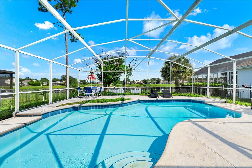A swimming pool with a screened enclosure overlooks a lake and residential neighborhood — 2619 HERON LANDING COURT, ORLANDO, FL