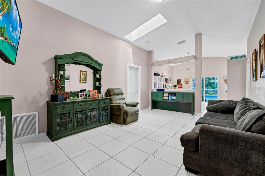 A living room with white tile floors, a green hutch, and a dark gray sofa — 2619 HERON LANDING COURT, ORLANDO, FL