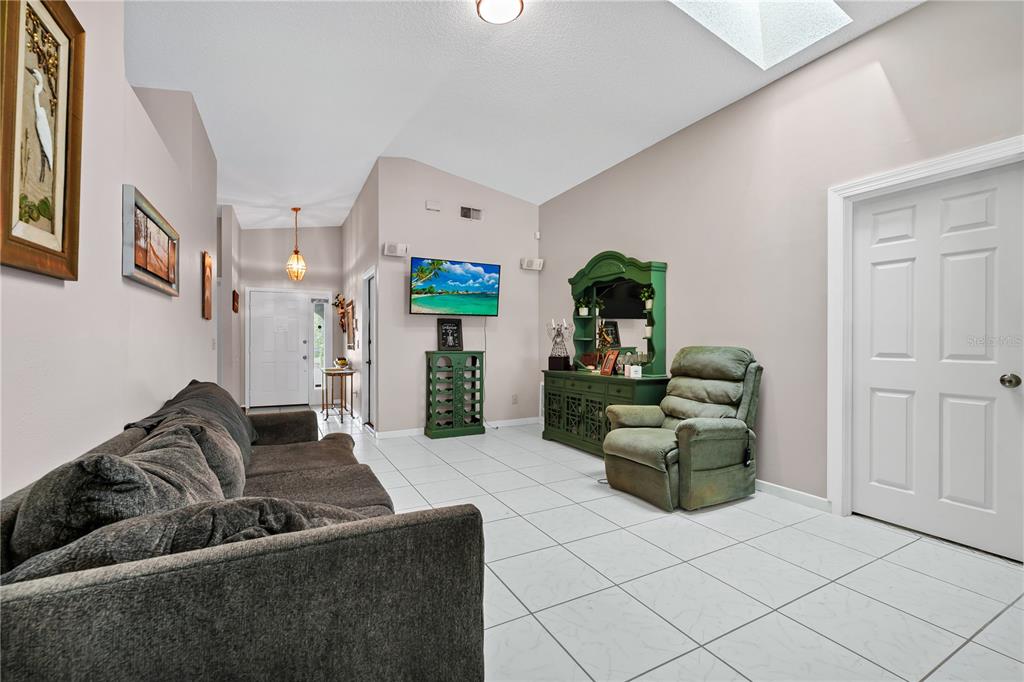 A living room with white tile floors, a vaulted ceiling, a sofa, and a recliner — 2619 HERON LANDING COURT, ORLANDO, FL