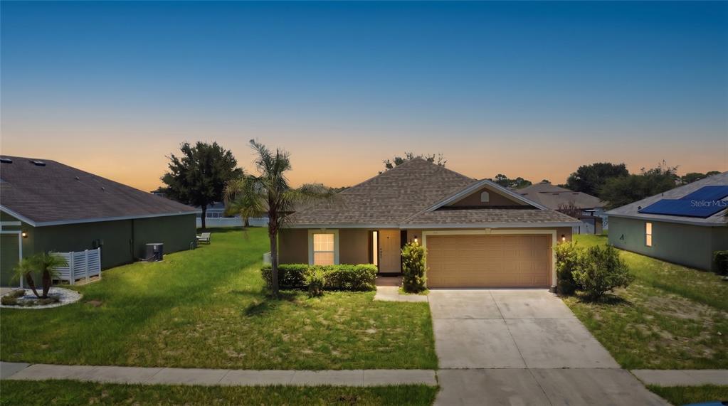 A single-story suburban house with a tan exterior, a two-car garage, and a palm tree — 184 ELEUTHERA DRIVE, LAKE ALFRED, FL
