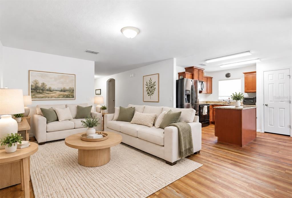 A living room features wood-look flooring, a dark leather sofa, and a wall-mounted television — 184 ELEUTHERA DRIVE, LAKE ALFRED, FL