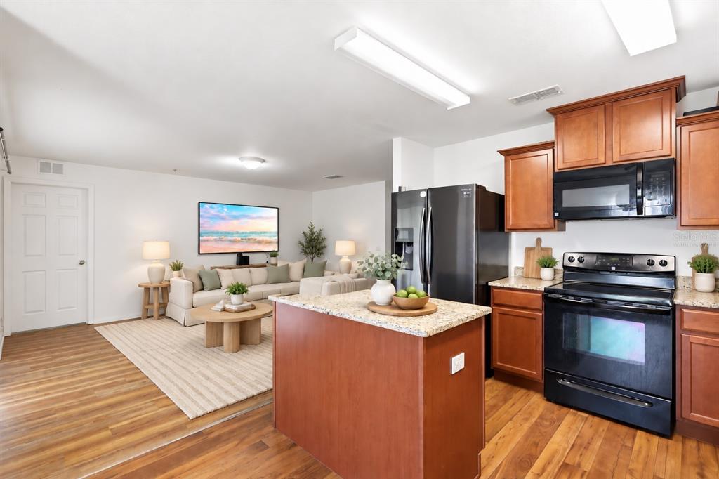 A living room features wood-look flooring, a dark leather sofa, and a wall-mounted television — 184 ELEUTHERA DRIVE, LAKE ALFRED, FL