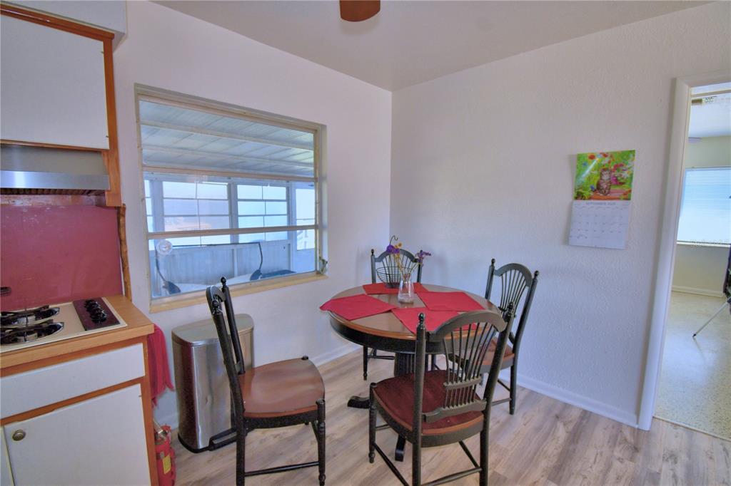A small dining area features a round table, wooden chairs, and a window overlooking a porch — 105 MAXCY LANE, FROSTPROOF, FL