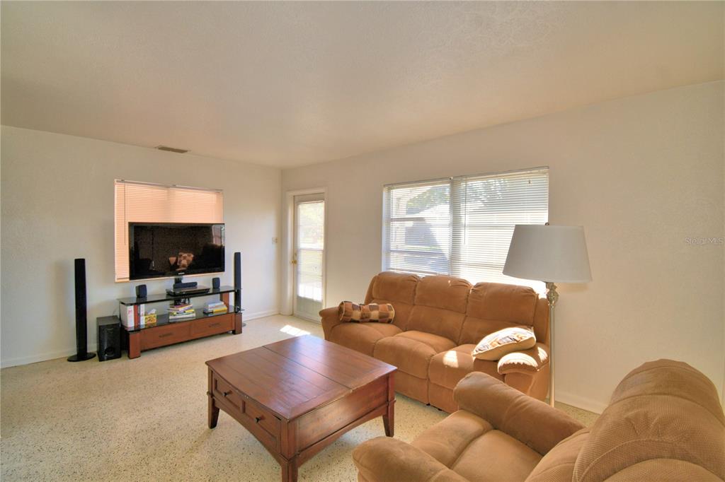 A living room features beige carpet, tan sofas, a wooden coffee table, and a television — 105 MAXCY LANE, FROSTPROOF, FL