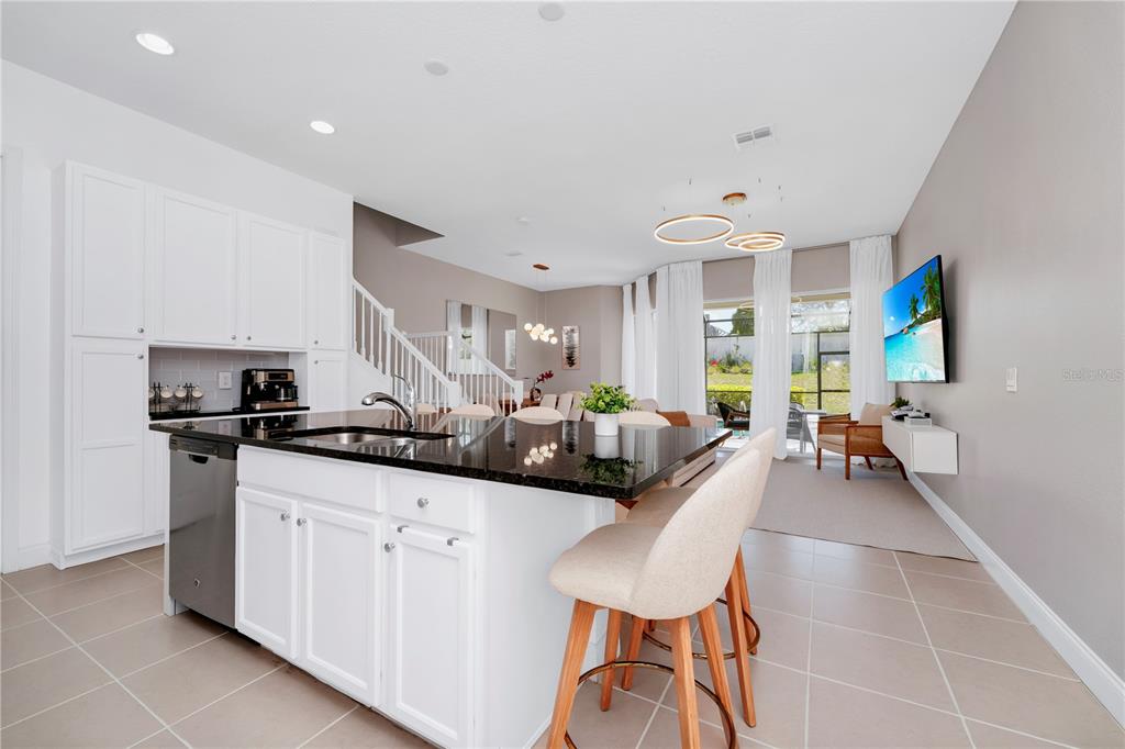 A kitchen island with black countertops sits in front of an open-concept living area — 302 CAPTIVA DRIVE, DAVENPORT, FL