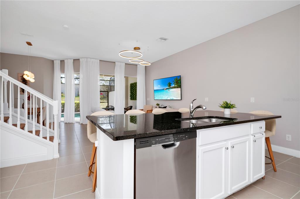 A kitchen island with a stainless steel dishwasher faces a living area with large windows — 302 CAPTIVA DRIVE, DAVENPORT, FL
