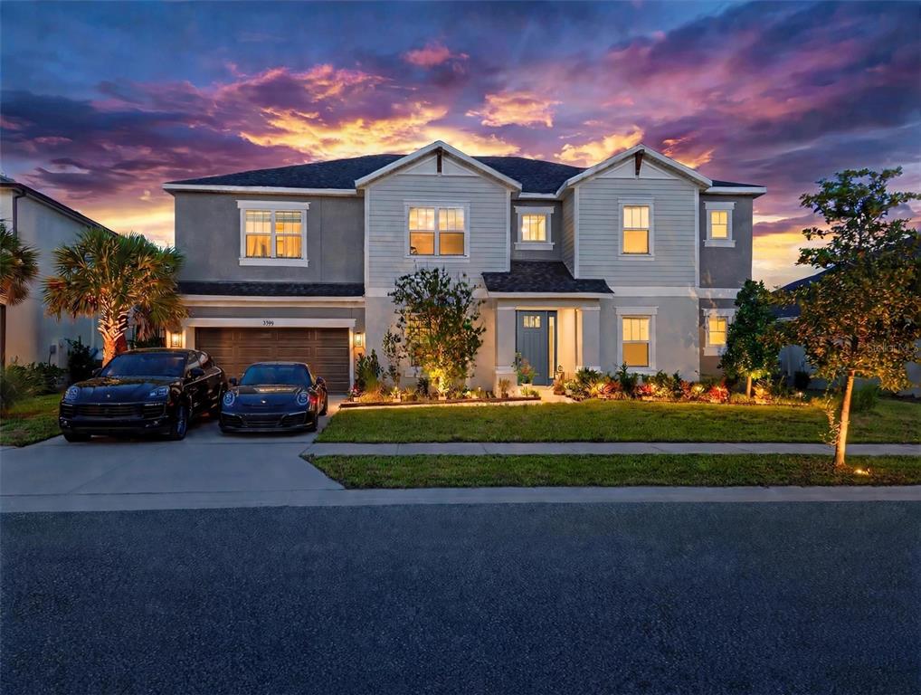 A two-story suburban house with a two-car garage and two parked cars at sunset — 7228 BRADBURY CIRCLE, WESLEY CHAPEL, FL