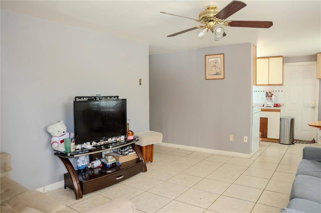 A living room features light tile flooring, a ceiling fan, and an open kitchen area — 638 DOGWOOD COURT, DUNEDIN, FL