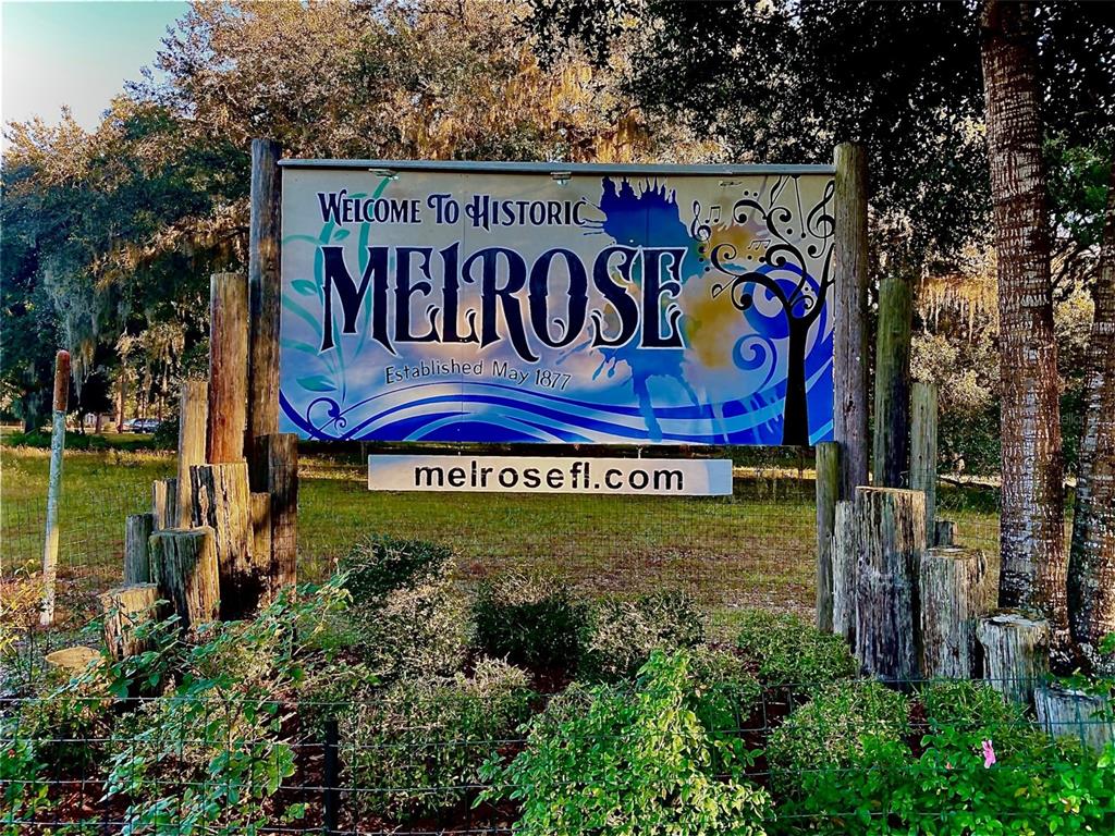 A sign reading Welcome to Historic Melrose stands outdoors among trees and landscaping — TROUT STREET, MELROSE, FL