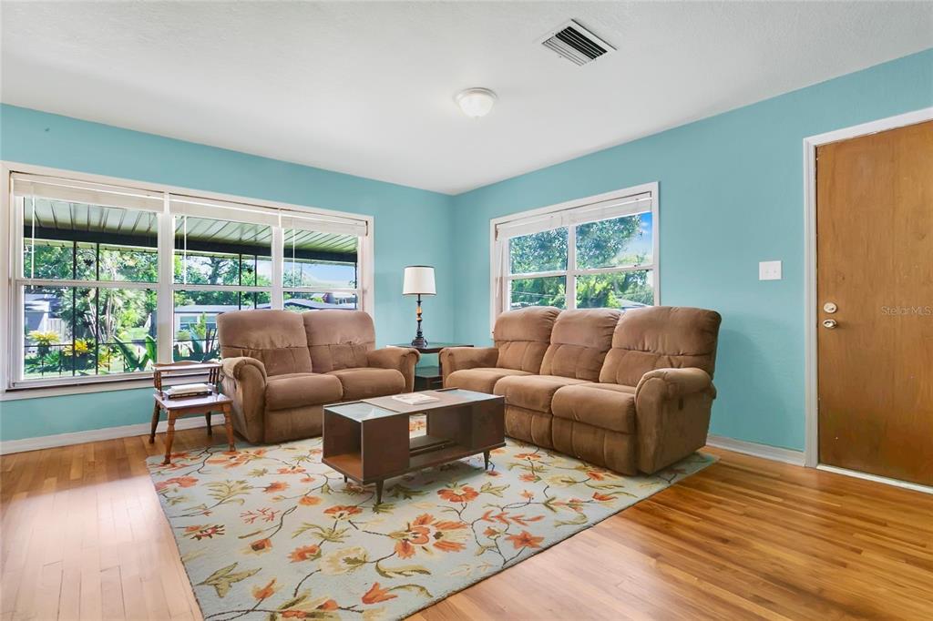 An open-concept living and dining area features light blue walls, hardwood floors, and white cabinetry — 2418 E JERSEY AVENUE, ORLANDO, FL