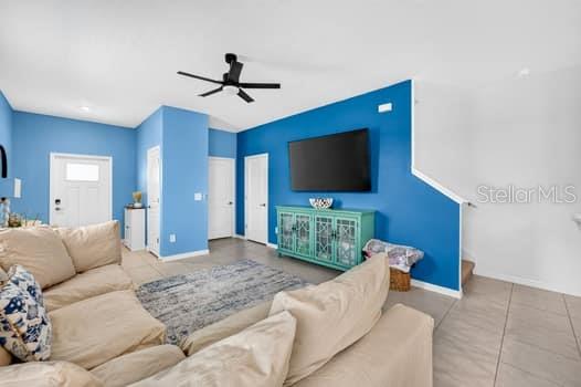 A living room features a blue accent wall, a mounted television, and beige sectional seating — 6119 SHINER STREET, LAND O LAKES, FL