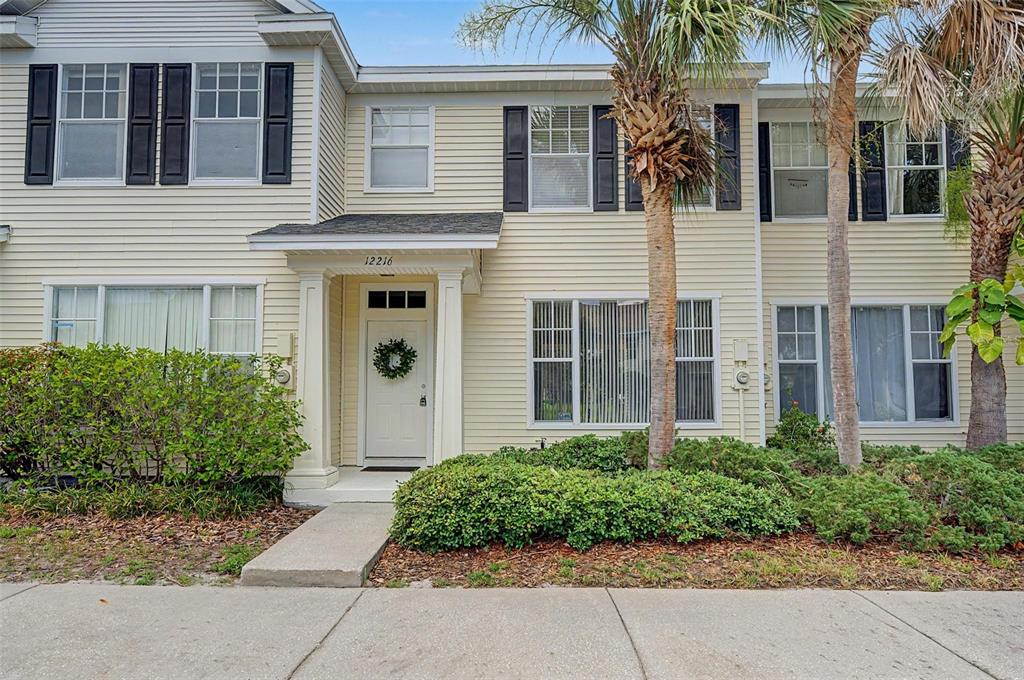 A two-story townhouse with light yellow siding, black shutters, and a front entrance — 12216 COUNTRY WHITE CIRCLE, TAMPA, FL