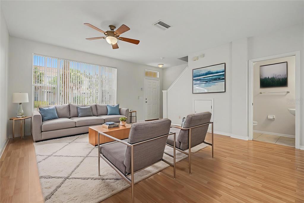 A living room features a gray sofa, two armchairs, a rug, and light wood flooring — 12216 COUNTRY WHITE CIRCLE, TAMPA, FL