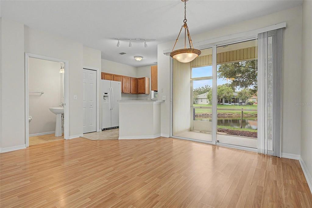 An open living area with wood-look flooring, a kitchen, and sliding doors to a patio — 12216 COUNTRY WHITE CIRCLE, TAMPA, FL
