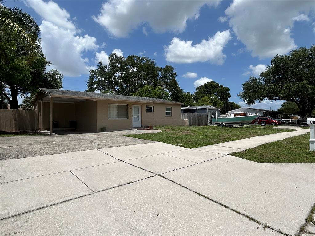 A single-story house with a carport, concrete driveway, and a boat parked on the lawn — 6971 78TH AVENUE N, PINELLAS PARK, FL
