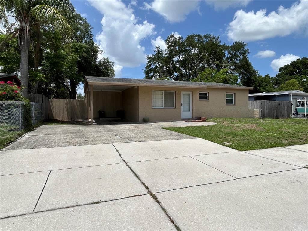 A single-story house with a tan exterior, a concrete driveway, and an attached carport — 6971 78TH AVENUE N, PINELLAS PARK, FL