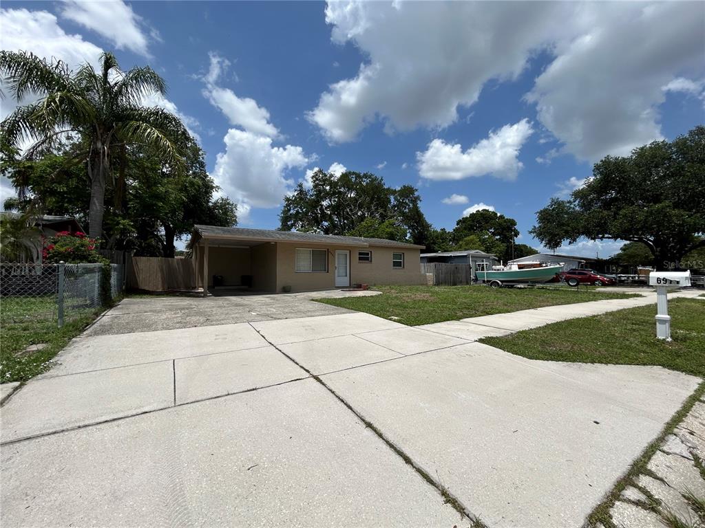 A single-story house with a carport and a concrete driveway under a cloudy sky — 6971 78TH AVENUE N, PINELLAS PARK, FL