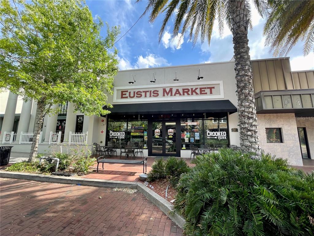 The exterior of a commercial building features a sign reading Eustis Market and Crooked Fork — 24 E MAGNOLIA AVENUE UNIT 5, EUSTIS, FL