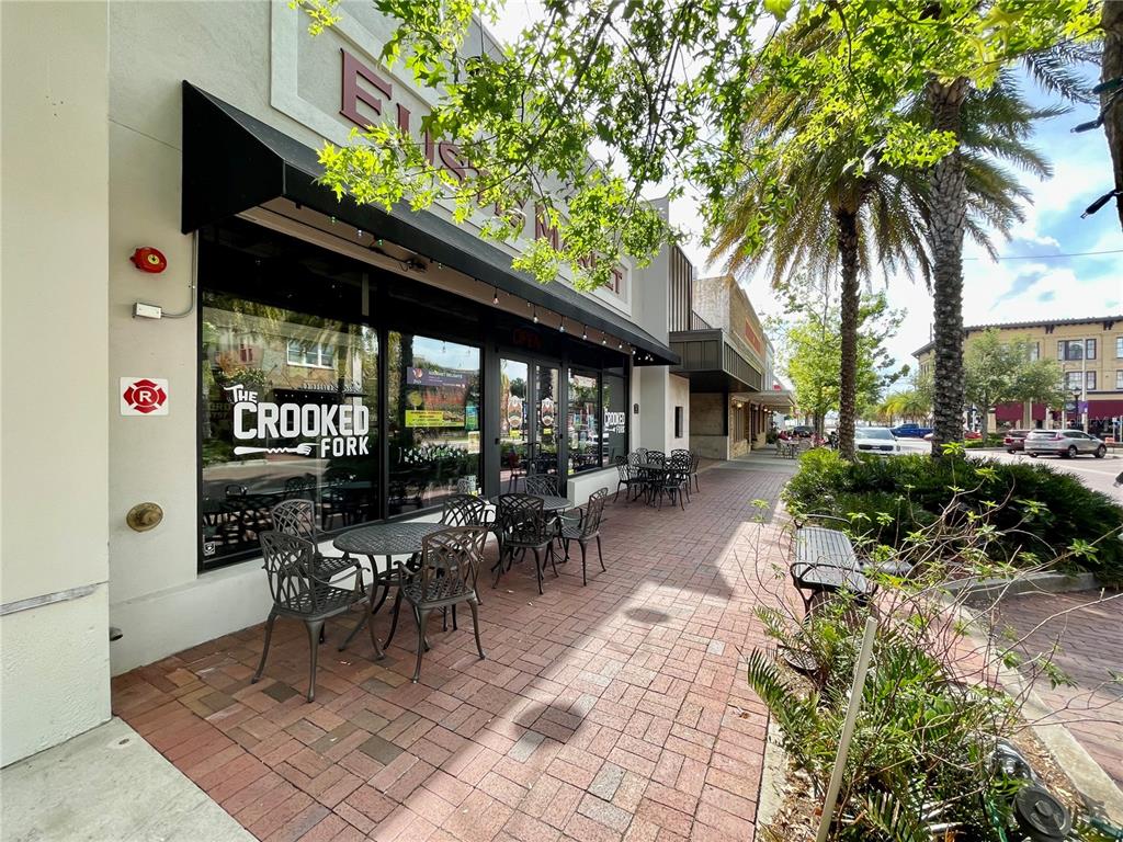 The exterior of a restaurant features outdoor seating on a brick sidewalk under an awning — 24 E MAGNOLIA AVENUE UNIT 5, EUSTIS, FL