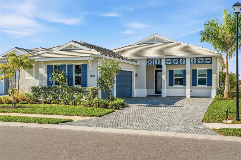 A single-story house with a paved driveway, blue shutters, and a tiled roof — 7982 REDONDA LOOP, BRADENTON, FL