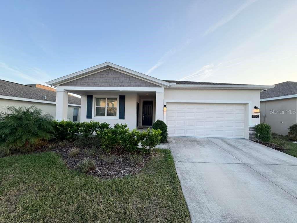 A single-story house with a white garage, a covered entryway, and a front lawn — 1180 SAGUARO STREET, HAINES CITY, FL