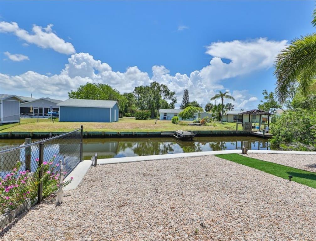 A gravel yard overlooks a narrow canal with a small dock and neighboring houses — 3503 W SHELL POINT ROAD, RUSKIN, FL