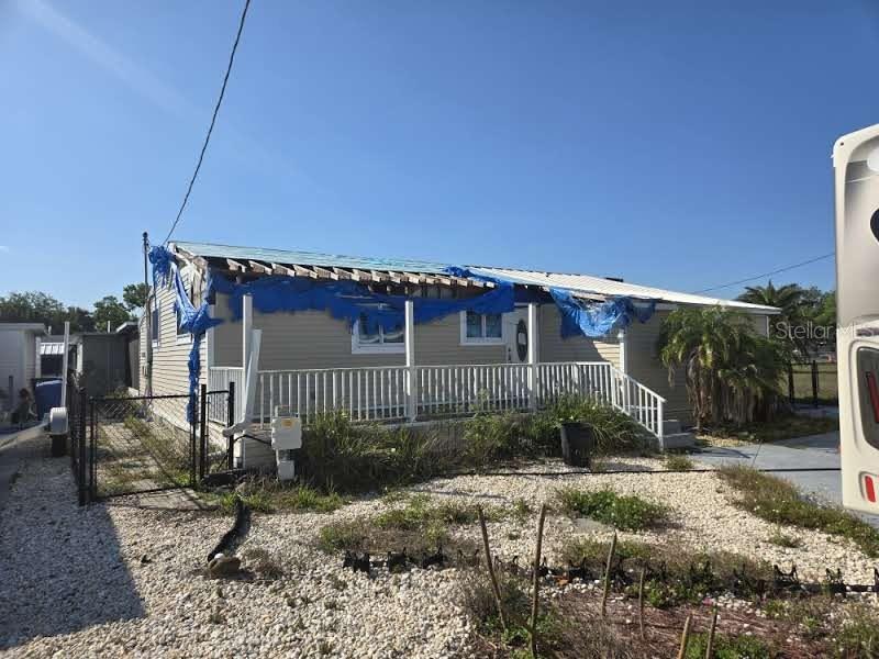 A single-story house with a damaged roof covered by a blue tarp and a front porch — 3503 W SHELL POINT ROAD, RUSKIN, FL