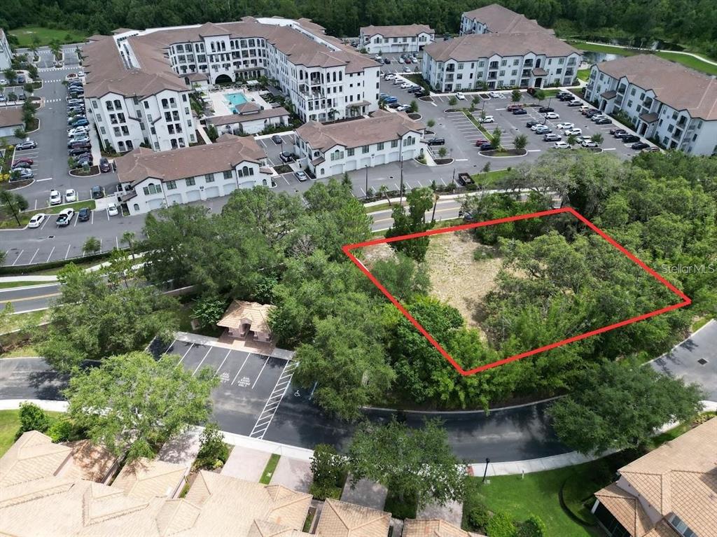 An aerial view shows a vacant, wooded lot outlined in red next to apartment buildings — 1320 S GOODMAN ROAD, DAVENPORT, FL
