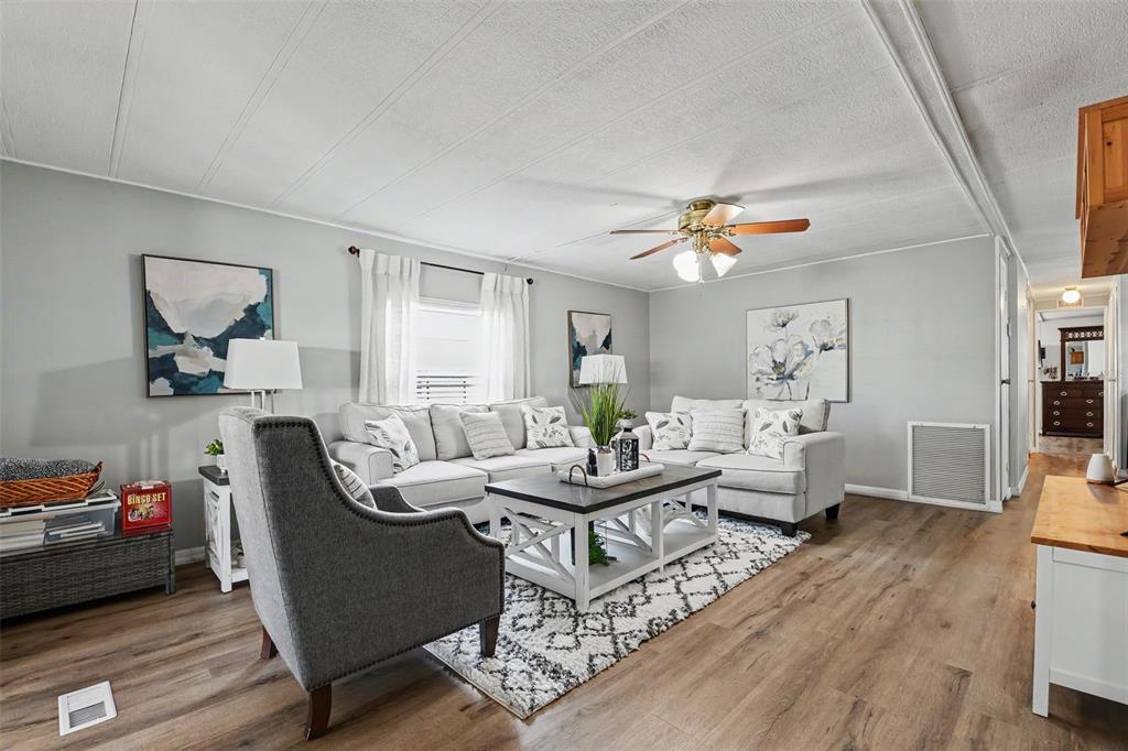 A living room with light gray walls, wood-look flooring, a sectional sofa, and a ceiling fan — 3902 JULIE DRIVE, WESLEY CHAPEL, FL
