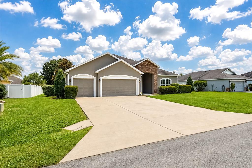 A single-story house with a three-car garage, stone facade accents, and a concrete driveway — 9857 SW 51ST COURT, OCALA, FL