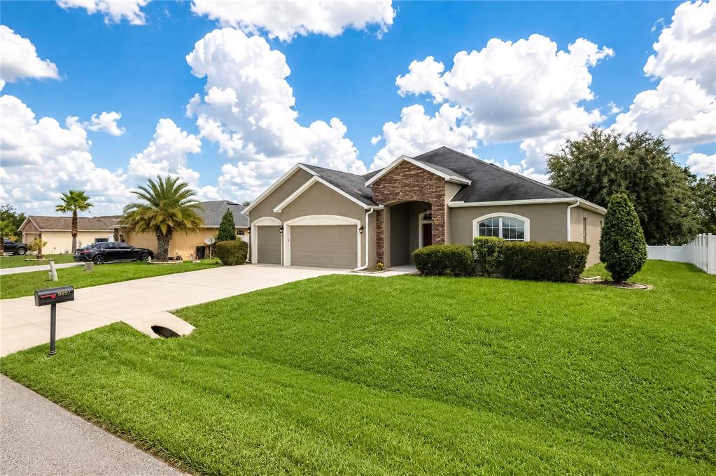 A single-story suburban house with a stone facade, a three-car garage, and a green lawn — 9857 SW 51ST COURT, OCALA, FL