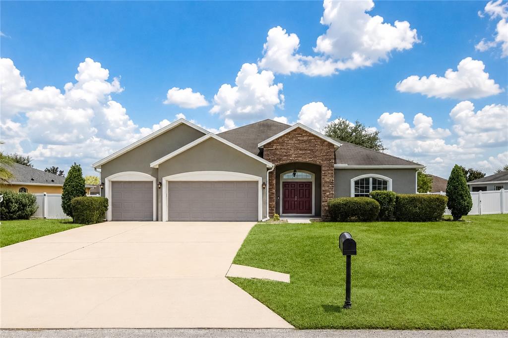 A single-story house with a three-car garage, stone facade, and a large front lawn — 9857 SW 51ST COURT, OCALA, FL