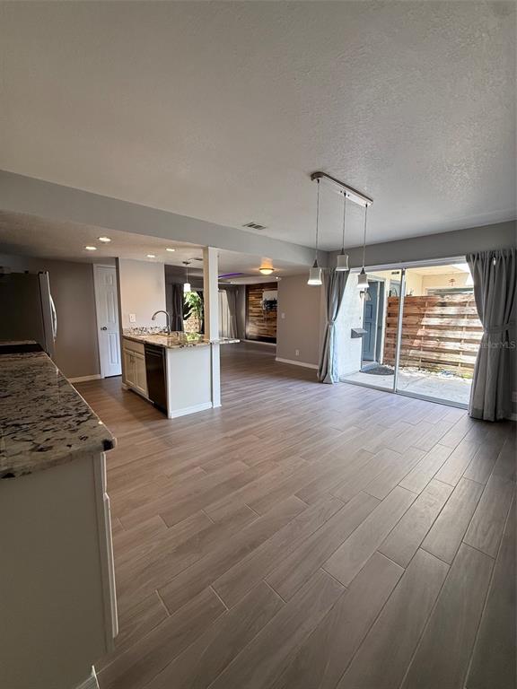 An open-concept kitchen and living area with wood-look tile flooring and sliding glass patio doors — 6814 WHITMAN PLACE UNIT 6814, SARASOTA, FL