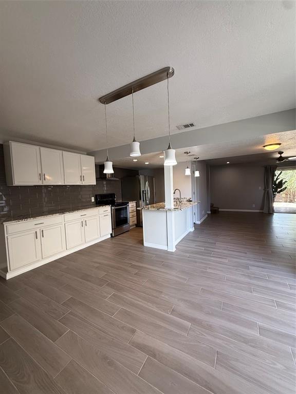 A kitchen with white cabinets, granite countertops, and wood-look tile flooring opens to a living area — 6814 WHITMAN PLACE UNIT 6814, SARASOTA, FL